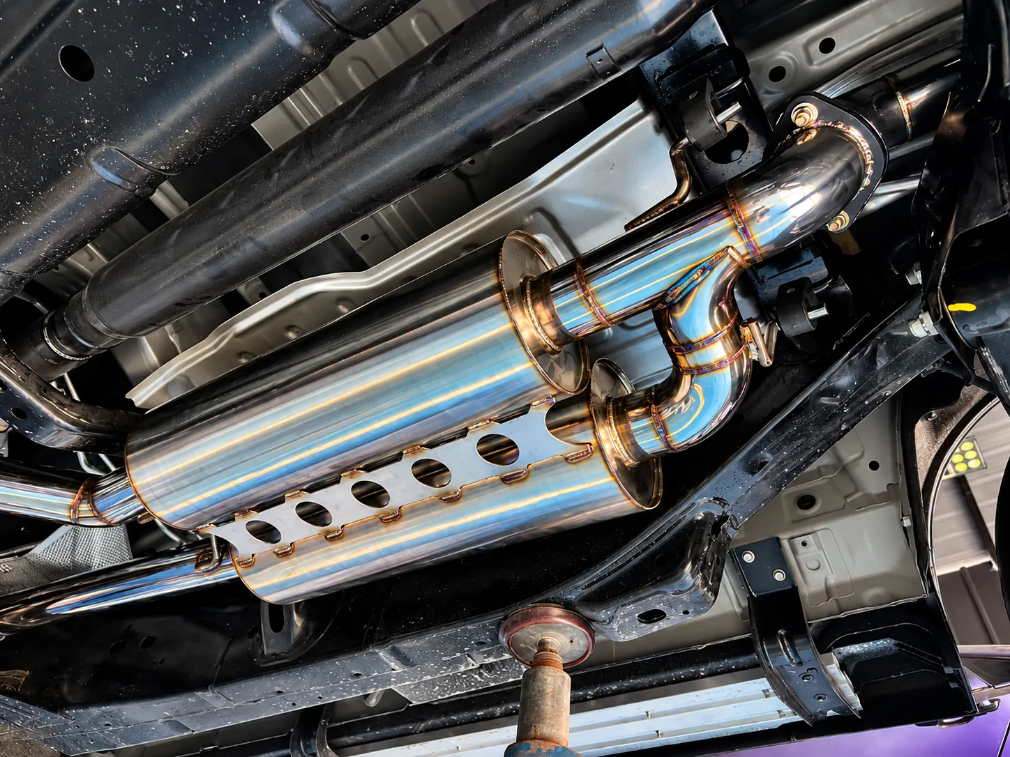 Custom fabricated stainless muffler with a heatshield under a vehicle