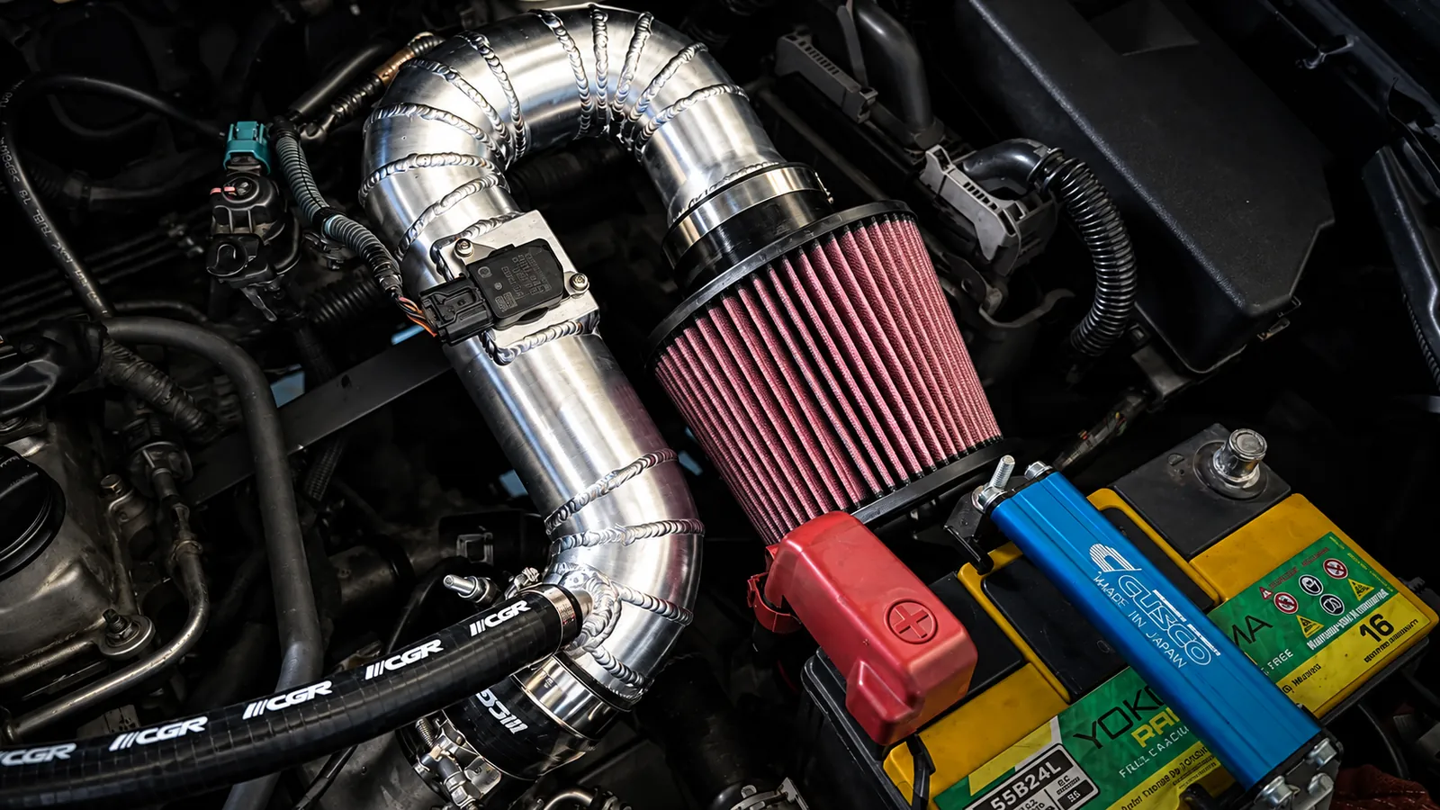 Custom aluminum intake piping with a red cone filter in an engine bay