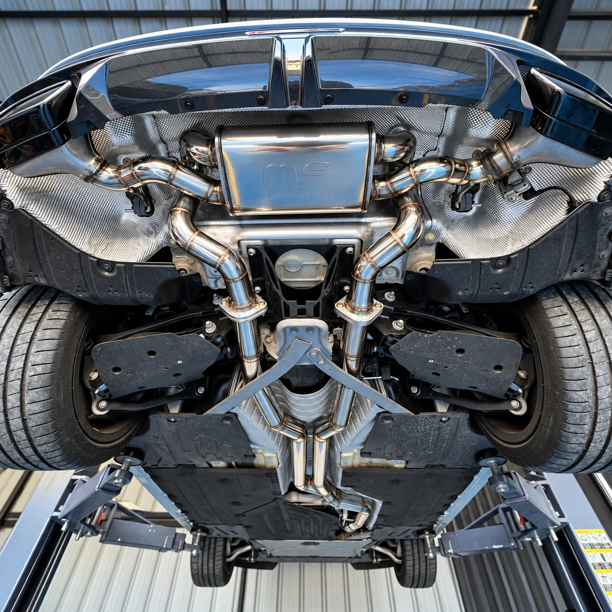 Underside of a BMW Z4 on the lift showing the custom stainless dual catback and Magnaflow muffler