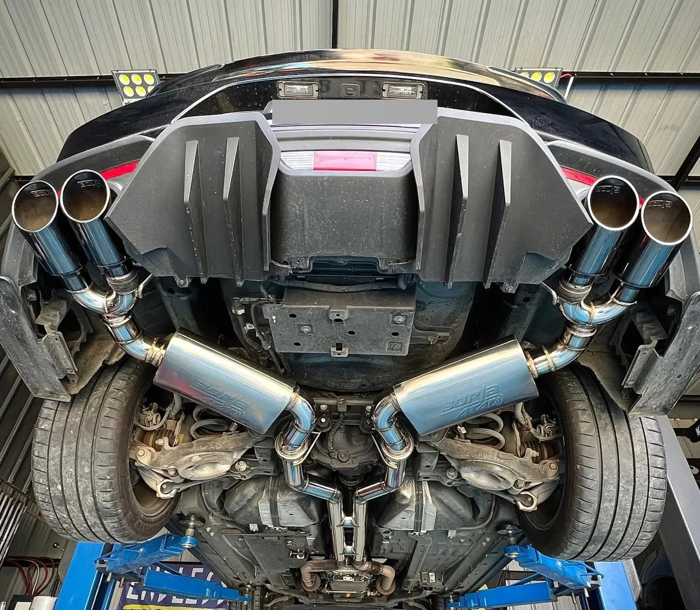 Underside of a Ford Mustang GT on the lift showing the double H-pipe dual catback, Borla ATAK mufflers and quad Borla tips